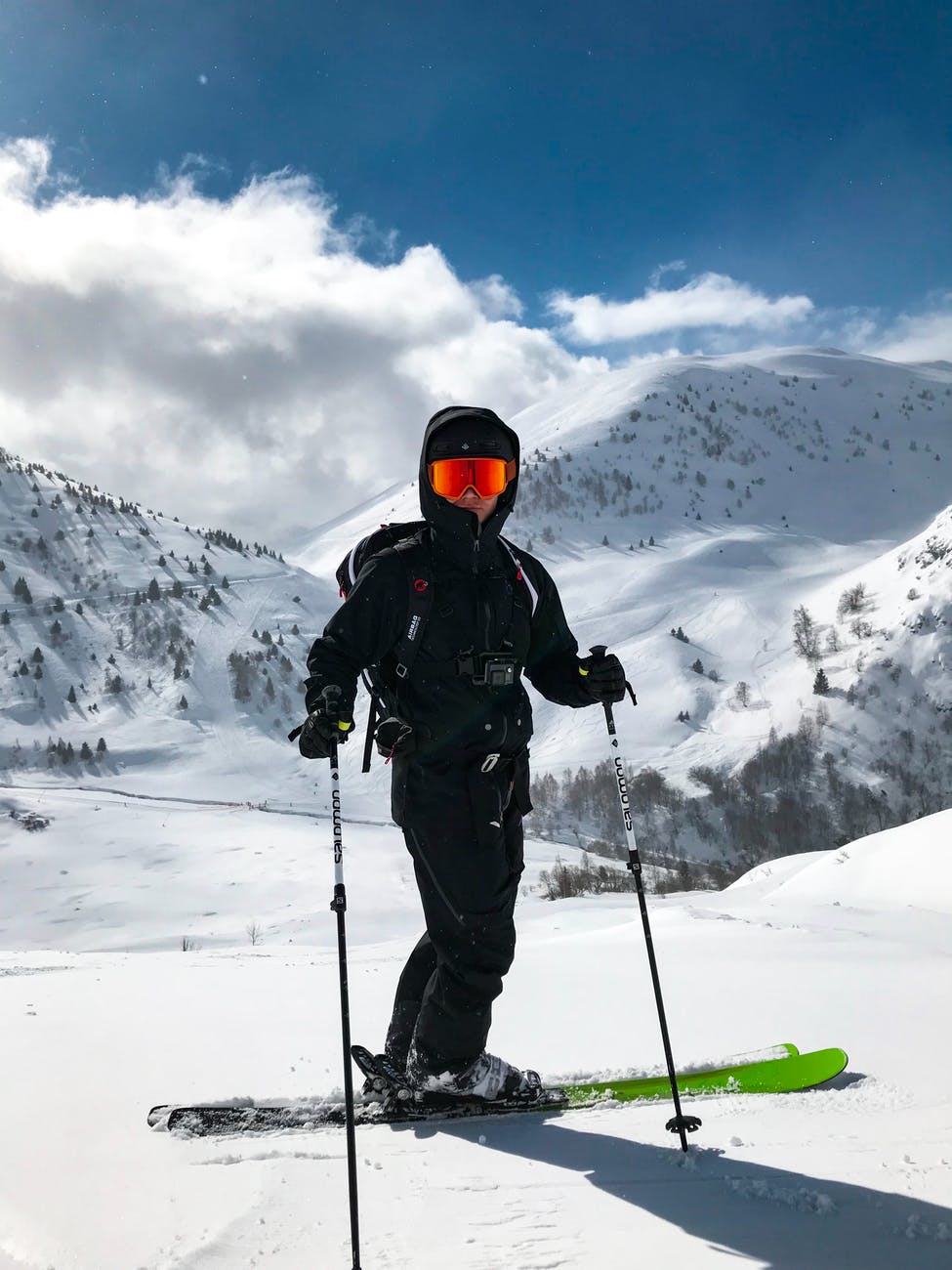 A person wearing black snowsuit and skies